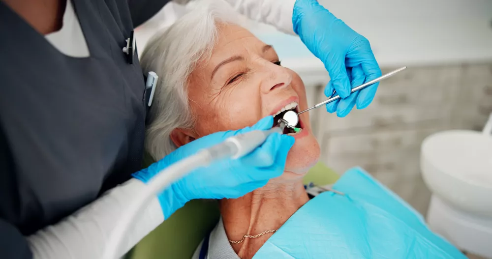 Cleaning, brush and senior woman at dentist for teeth whitening treatment, dentures or oral hygiene. Healthcare, chair and elderly patient in clinic for polish, dental care or plaque with tools / Foto: Jacob Wackerhausen