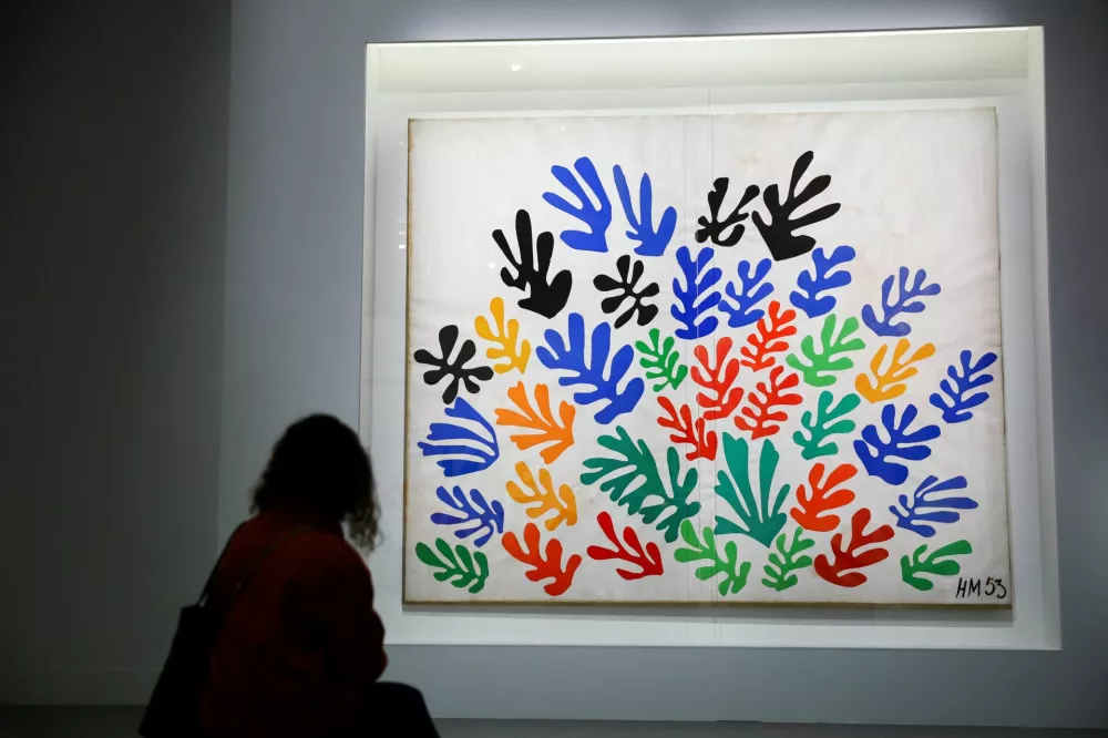 A woman sits in front of the painting "La Gerbe, 1953" (The Sheaf, 1953) by painter Henri Matisse (1869-1954) during a press visit of the exhibition "Matisse, 1941 - 1954" at the Grand Palais in Paris, France, March 23, 2026. REUTERS/Sarah Meyssonnier