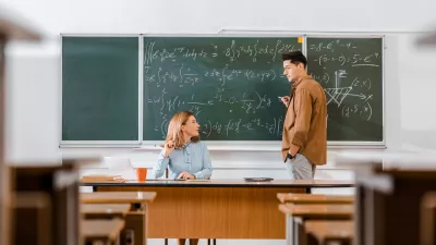 male student looking at female teacher and solving equations during lesson in classroom / Foto: Lightfieldstudios