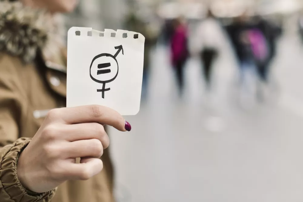 closeup of a young caucasian woman in the street showing a piece of paper with a symbol for gender equality drawn in it / Foto: Nito100