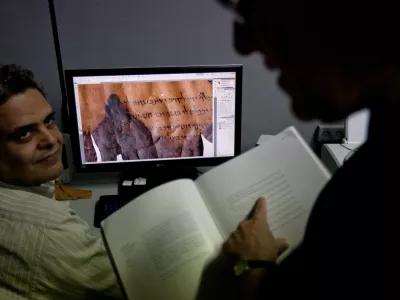 Photographer Yair Medina, left, shows Pnina Shor, right, curator and Head of Dead Sea Scrolls Project at the Israel Antiquities Authority, IAA, scanned fragments of the Dead Sea Scrolls on a computer screen, at the IAA offices at the Israel Museum in Jerusalem, Monday, Sept. 26, 2011. Two thousand years after they were written and decades after they were found in desert caves, some of the world-famous Dead Sea Scrolls are available online. Israel's national museum and the international web giant Google are behind the project, which saw five scrolls go online Monday. (AP Photo/Sebastian Scheiner)