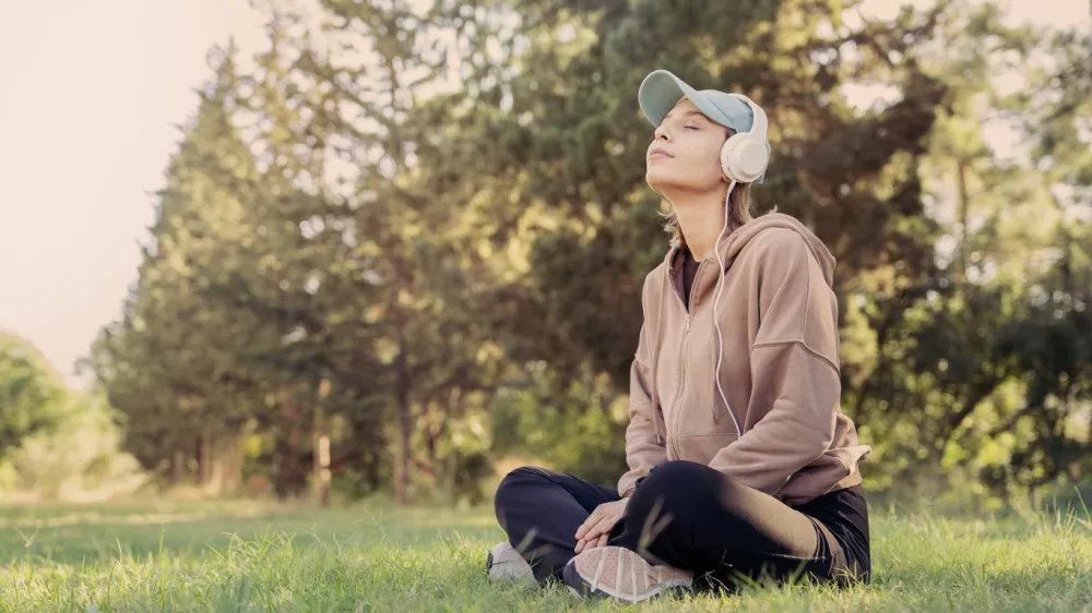 Woman listening to music with headphones in the nature / Foto: Seb_ra Getty Images