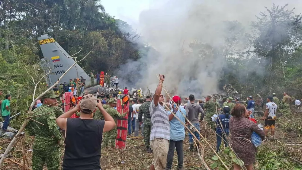 People stand around a military cargo plane that crashed after taking off from Puerto Leguizamo, Colombia, a remote municipality in the Amazonian province of Putumayo, Monday, March 23, 2026. (MiPutumayo via AP)