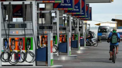 A motorcycle rider enters a gasoline station while a bicycle passes by on Wednesday, March 25, 2026, in Paranaque city, Philippines. (AP Photo/Aaron Favila)