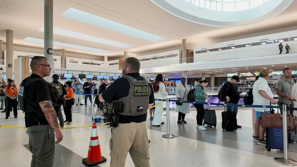 Two Immigration and Customs Enforcement (ICE) agents observe passengers waiting in long TSA lines amid a funding standoff that has forced 50,000 airport security officers to go without pay, causing delays at airports, at the George Bush Intercontinental Airport in Houston, Texas, U.S., March 25, 2026, in this screengrab from video. REUTERS/Evan Garcia