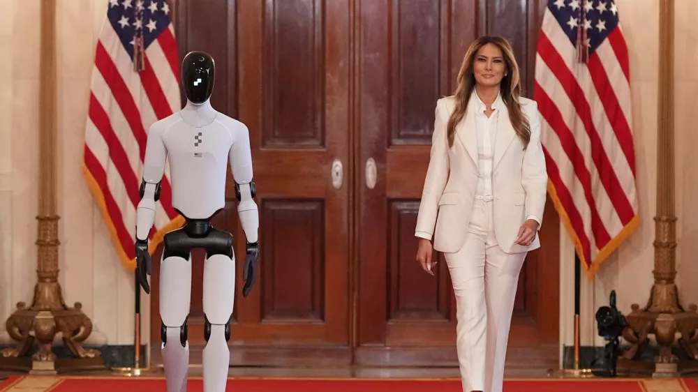 First lady Melania Trump arrives, accompanied by a robot, to attend the "Fostering the Future Together Global Coalition Summit," with other first spouses, at the White House, Wednesday, March 25, 2026, in Washington. (AP Photo/Jacquelyn Martin)