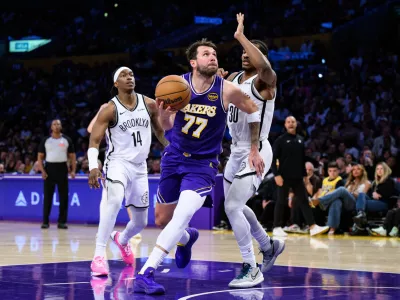 Mar 27, 2026; Los Angeles, California, USA; Los Angeles Lakers guard Luka Doncic (77) drives against Brooklyn Nets guards Ochai Agbaji (30) and Terance Mann (14) during the second half at Crypto.com Arena. Mandatory Credit: William Liang-Imagn Images
