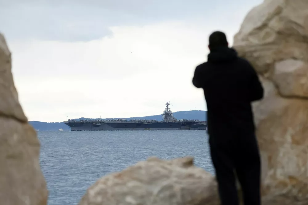 A person looks on as U.S. aircraft carrier "Gerald R. Ford" holds position in front of Split, in the Adriatic Sea, March 28, 2026. REUTERS/Antonio Bronic
