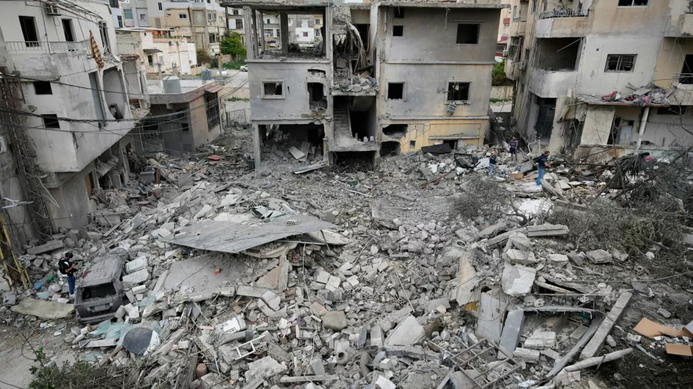 Journalists check the site of a destroyed building that was hit in an Israeli airstrike in the southern port city of Tyre, Lebanon, Thursday, March 26, 2026. (AP Photo/Hussein Malla)