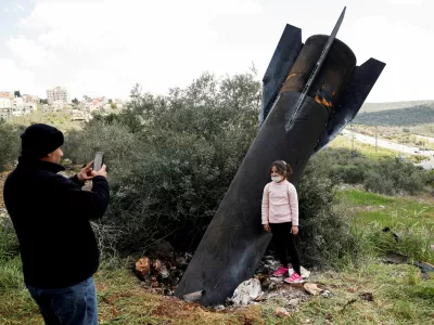 FILE PHOTO: A girl poses for a picture next to the remnants of a missile stuck in the ground found in Kifl Haris village, near Nablus in the Israeli-occupied West Bank, March 24, 2026. REUTERS/Mohammed Torokman/File Photo