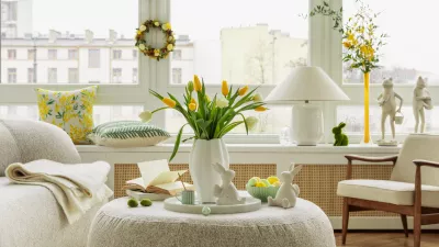 Bright living room with an Easter setup featuring yellow tulips in a white vase, soft textured pillows, and delicate decorations, creating a warm and festive ambiance.