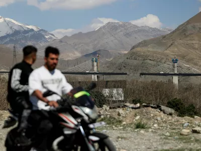Men ride on a motorbike with the B1 bridge damaged by a strike in the background, as the U.S.-Israeli conflict with Iran continues, in Karaj, Iran, April 3, 2026. Majid Asgaripour/WANA (West Asia News Agency) via REUTERS ATTENTION EDITORS - THIS PICTURE WAS PROVIDED BY A THIRD PARTY