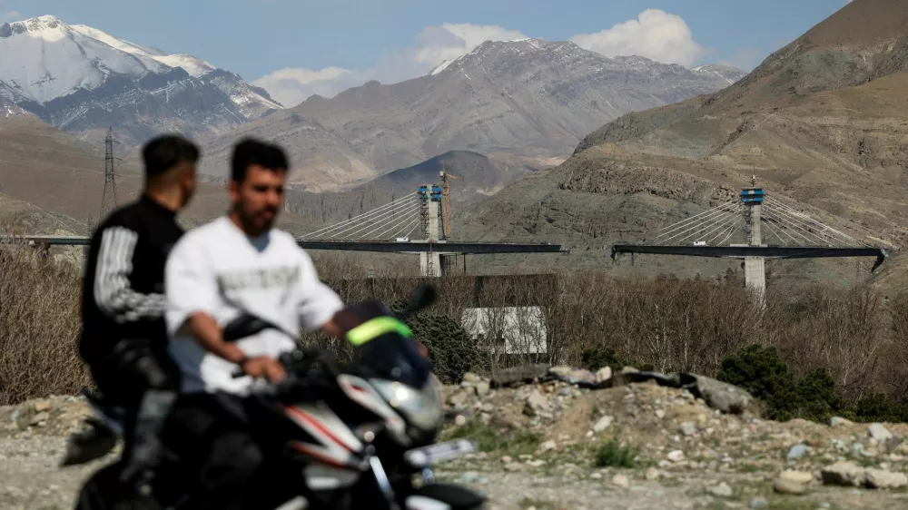 Men ride on a motorbike with the B1 bridge damaged by a strike in the background, as the U.S.-Israeli conflict with Iran continues, in Karaj, Iran, April 3, 2026. Majid Asgaripour/WANA (West Asia News Agency) via REUTERS ATTENTION EDITORS - THIS PICTURE WAS PROVIDED BY A THIRD PARTY
