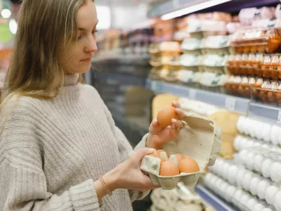 Woman chooses chicken eggs in a farm food store. Food consumption, Easter. / Foto: Vladdeep
