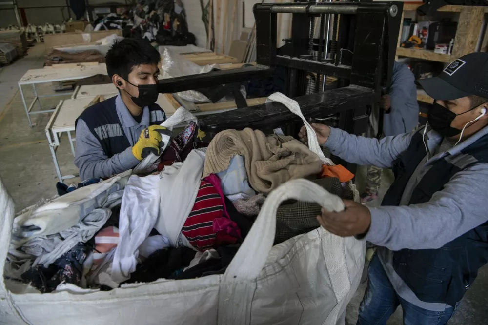 Men work at a factory that recycles used clothes discarded in the Atacama desert for wooden isolation panels for the walls of social housing, in Alto Hospicio, Iquique, Chile, on September 27, 2021. EcoFibra, Ecocitex and Sembra are circular economy projects that have textile waste as their raw material. The textile industry in Chile will be included in the law of Extended Responsibility of the Producer (REP), forcing clothes and textiles importers take charge of the waste they generate.,Image: 642069796, License: Rights-managed, Restrictions: TO GO WITH AFP STORY BY PAULA BUSTAMANTE, Model Release: no