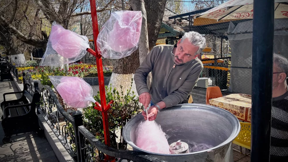 A man spins cotton candy for passersby in a public park near Road 2 in Tabriz, Iran, Thursday, April 9, 2026. (AP Photo/Francisco Seco)