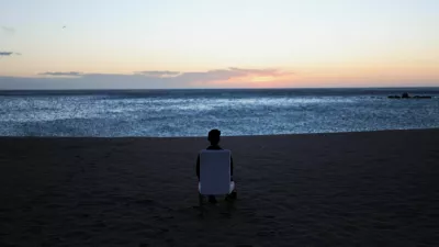 A tourist sits on a chair and looks out at sunrise on a beach in Barcelona, Spain, February 12, 2026. REUTERS/Nacho Doce / Foto: Nacho Doce