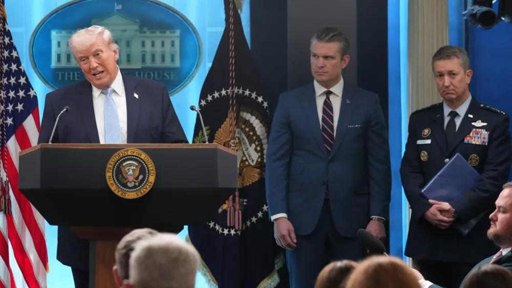 FILE - President Donald Trump speaks with reporters during a news conference in the James Brady Press Briefing Room at the White House, Monday, April 6, 2026, in Washington, as Defense Secretary Pete Hegseth and Chairman of the Joint Chiefs of Staff Gen. Dan Caine listen. (AP Photo/Mark Schiefelbein, File)