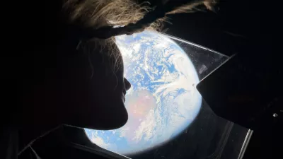 This image provided by NASA, astronaut and Artemis II mission specialist Christina Koch peers out of one of the Orion spacecraft's main cabin windows, looking back at Earth, as the crew travels towards the Moon on Thursday, April 2, 2026. (NASA via AP)