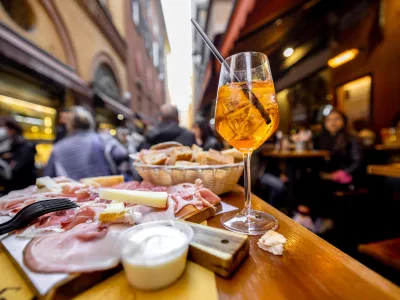 Meat plate with sliced italian sausages, proscutto, cheese, bread and Spritz Aperol drink on a table at outdoor bar on crowded street background / Foto: Rosshelen Getty Images/istockphoto