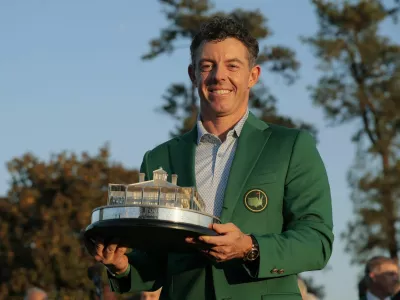 Golf - The Masters - Augusta National Golf Club, Augusta, Georgia, U.S. - April 12, 2026 Northern Ireland's Rory McIlroy celebrates with his green jacket and the trophy after winning The Masters REUTERS/Brian Snyder