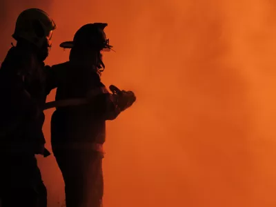 Rear view of Asian fireman wear fire protection suit. Firefighter spray water fighting. Emergency, Fire! at night
