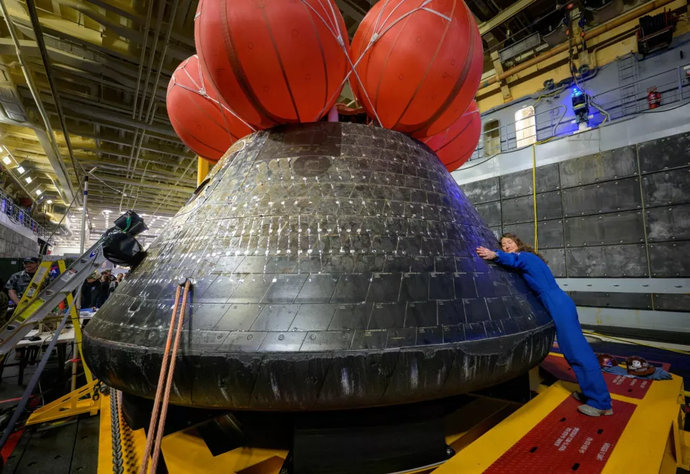 NASA astronaut Christina Koch hugs the Orion spacecraft in the well deck of the U.S. Navy ship USS John P. Murtha a day after her crew splashed down in the Pacific Ocean off the coast of California, U.S. April 11, 2026. NASA/Bill Ingalls/Handout via REUTERS THIS IMAGE HAS BEEN SUPPLIED BY A THIRD PARTY. MANDATORY CREDIT.   TPX IMAGES OF THE DAY