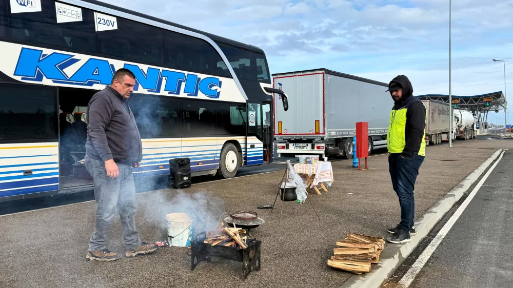 A man prepares to cook on a portable grill next to a line of trucks and buses on the Bosnian side of the border with Croatia, in Svilaj, Bosnia, Monday, Jan. 26, 2026, as drivers across the Balkans blocked dozens of border crossings in the region in protest over newly introduced European Union entry regulations.(AP Photo/Eldar Emric)