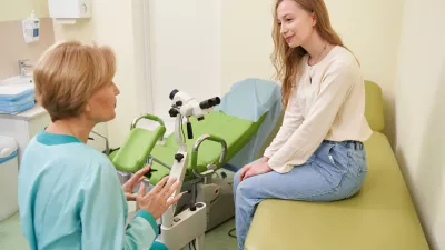 Professional female doctor looking at her patient and discussing female disorders