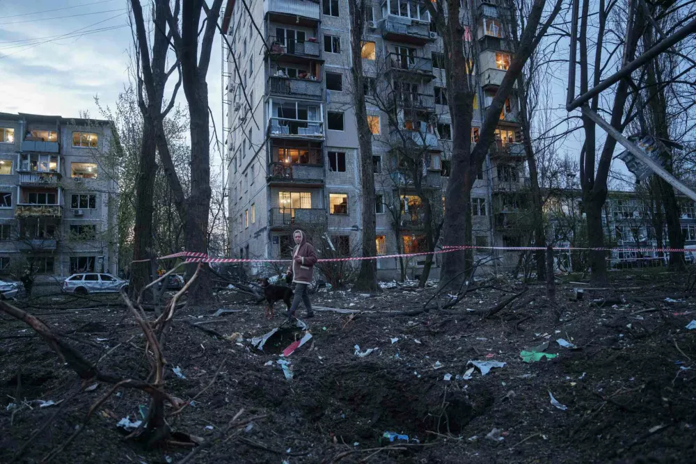 A woman with a dog walks among the rubble of a house damaged after a Russian strike on residential area in Kyiv, Ukraine, on Thursday, April 16, 2026. (AP Photo/Evgeniy Maloletka)