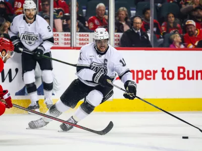 Apr 16, 2026; Calgary, Alberta, CAN; Los Angeles Kings center Anze Kopitar (11) controls the puck against Calgary Flames right wing Matt Coronato (27) during the first period at Scotiabank Saddledome. Mandatory Credit: Sergei Belski-Imagn Images