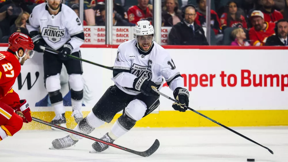 Apr 16, 2026; Calgary, Alberta, CAN; Los Angeles Kings center Anze Kopitar (11) controls the puck against Calgary Flames right wing Matt Coronato (27) during the first period at Scotiabank Saddledome. Mandatory Credit: Sergei Belski-Imagn Images