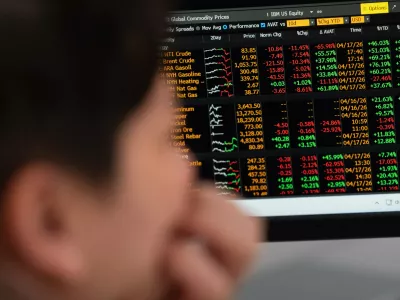 Global commodity prices including energy are displayed behind Portland State University guest teacher Khanh Anastasiou Vu in the finance lab on campus on Friday, April 17, 2026, in Portland, Ore. (AP Photo/Jenny Kane)