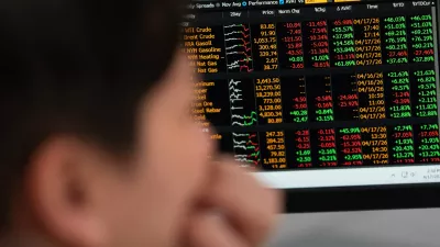 Global commodity prices including energy are displayed behind Portland State University guest teacher Khanh Anastasiou Vu in the finance lab on campus on Friday, April 17, 2026, in Portland, Ore. (AP Photo/Jenny Kane)