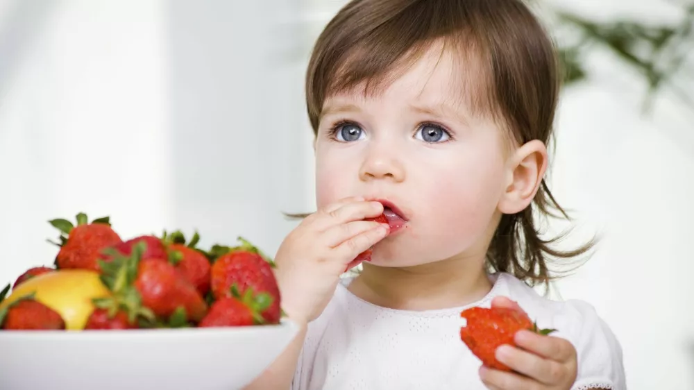 a little girl eating strawberries