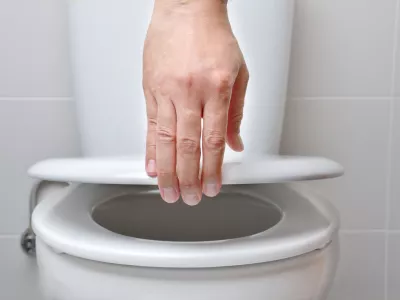hand of a man closing the lid of a toilet