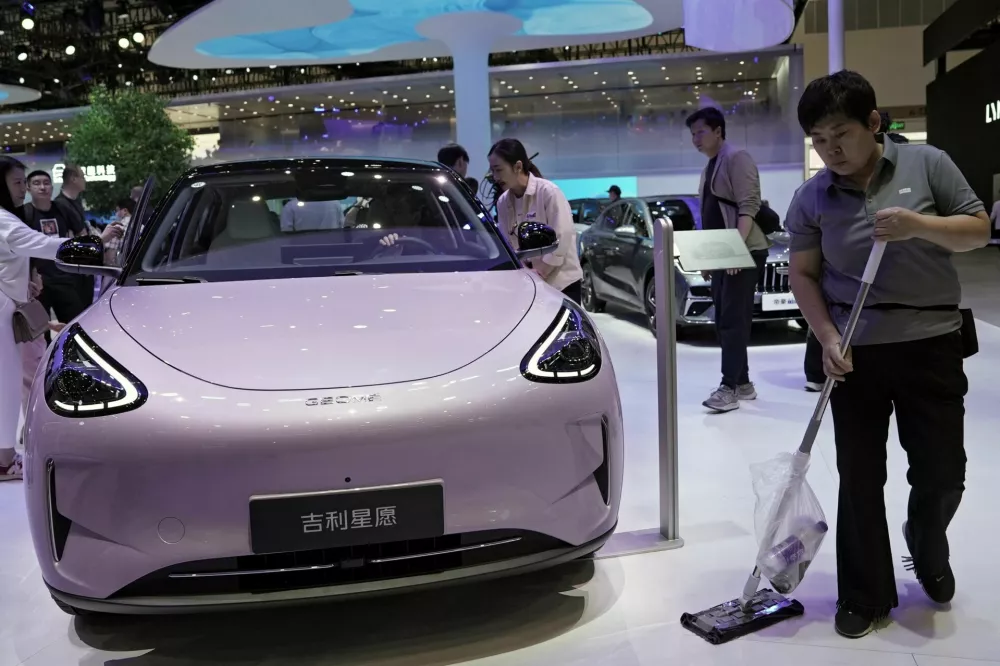 A staff member cleans the floor next to a Geely GEOME Xingyuan electric vehicle (EV), also known as Geely EX2, displayed at the Beijing International Automotive Exhibition, or Auto China, in Beijing, China April 26, 2026. REUTERS/Xiaoyu Yin