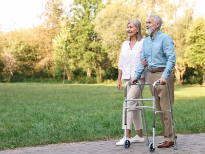 Senior couple with walking frame in park, space for text / Foto: Olga Yastremska