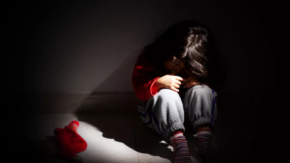 young girl sitting down alone in the dark.