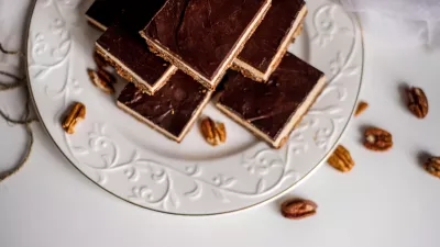 Very appetizing beautiful food photo of tasty chocolate authentic canadian dessert Nanaimo with nuts in healthy version - plant based and shugar free. Served on the elegant white plate on a white background. / Foto: Anton Parshunas