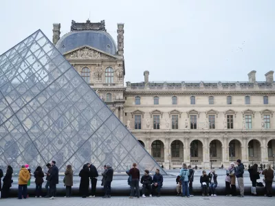 FILE - People wait for the Louvre museum to open as employees at the Louvre Museum vote to extend a strike that has disrupted operations at the world's most visited museum, Dec. 18, 2025 in Paris. (AP Photo/Thibault Camus, File)