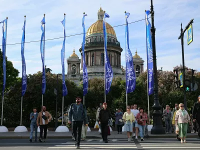 People cross the street near flags with the logo of the St. Petersburg International Economic Forum (SPIEF) flying in front of the St. Isaac's Cathedral on the eve of the forum's opening in Saint Petersburg, Russia June 2, 2026. REUTERS/Anastasia Barashkova