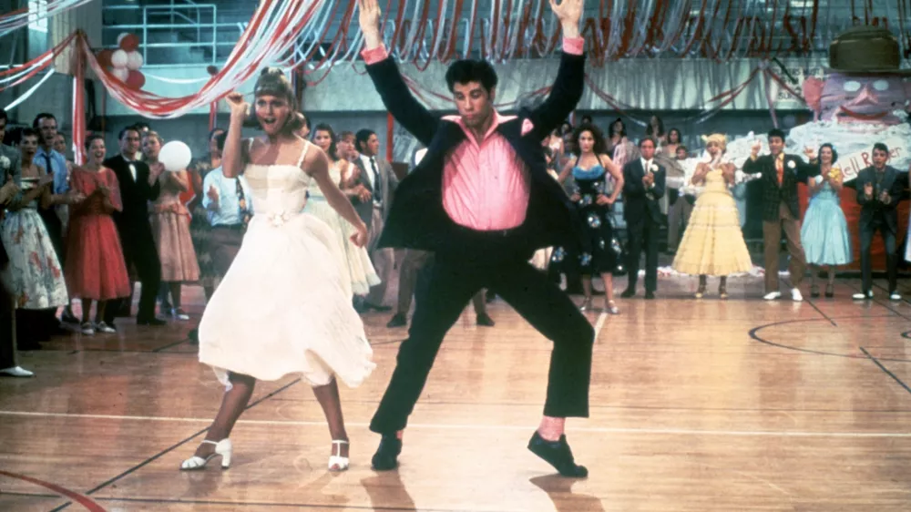 1978: Australian singer and actor Olivia Newton-John and American actor John Travolta dance in a crowded high school gym in a still from the film, 'Grease,' directed by Randal Kleiser. (Photo by Paramount Pictures/Fotos International/Getty Images)