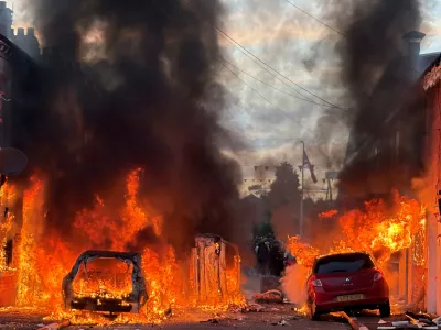 Vehicles set on fire by protesters burn on Lendrick Street in east Belfast, Northern Ireland, on Tuesday, June 9, 2026, after the arrest of a Sudanese man accused of stabbing a man in the northern part of the city. (PA via AP)