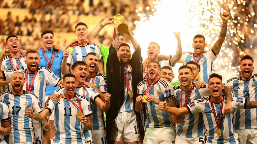 Soccer Football - FIFA World Cup Qatar 2022 - Final - Argentina v France - Lusail Stadium, Lusail, Qatar - December 18, 2022 Argentina's Lionel Messi lifts the World Cup trophy alongside teammates as they celebrate after winning the World Cup REUTERS/Kai Pfaffenbach