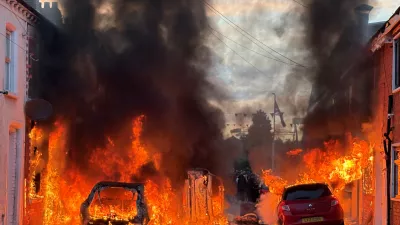 Vehicles set on fire by protesters burn on Lendrick Street in east Belfast, Northern Ireland, on Tuesday, June 9, 2026, after the arrest of a Sudanese man accused of stabbing a man in the northern part of the city. (PA via AP)