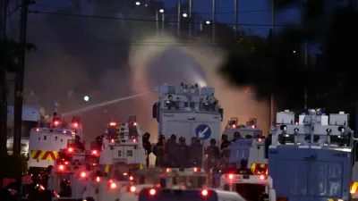 Police fire a water cannon towards rioters after they set fire to wheelie bins and removed a garden fence to use as a shield against the water cannon in Newtownabbey, Belfast, Northern Ireland, Wednesday June 10, 2026. (PA via AP)
