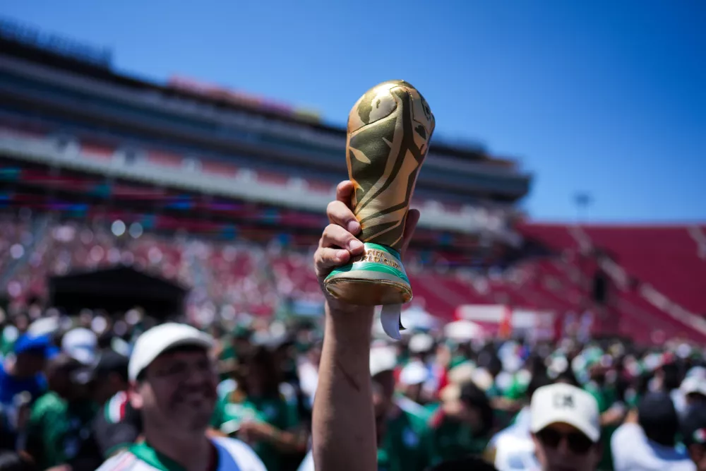 A fan holds up a replica of the World Cup trophy at a fan festival at the Los Angeles Memorial Coliseum in Los Angeles, Thursday, June 11, 2026, during a live broadcast of the World Cup soccer match between Mexico and South Africa. (AP Photo/Jae C. Hong)