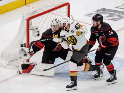 Carolina Hurricanes' Brandon Bussi (32) reaches for the puck ahead of Sean Walker (26) as Vegas Golden Knights' Colton Sissons (10) attempts a shot during the third period of Game 5 of the NHL hockey Stanley Cup Final series in Raleigh, N.C., Thursday, June 11, 2026. (AP Photo/Ben McKeown)