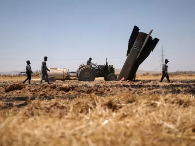 Farmers spray water in a burned agricultural field next to a projectile near the town of Najha, Syria, Monday, June 8, 2026, after debris from Iranian missile launches during the Iran-Israel conflict fell in the area. (AP Photo/Ghaith Alsayed)